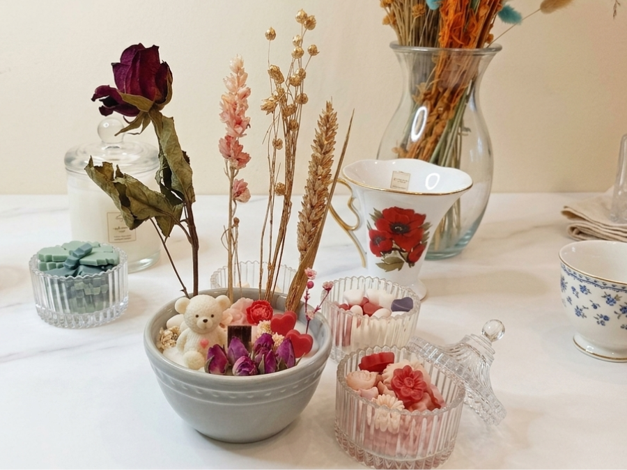 Table de créations de l'atelier : bougies décorées et fleurs séchées